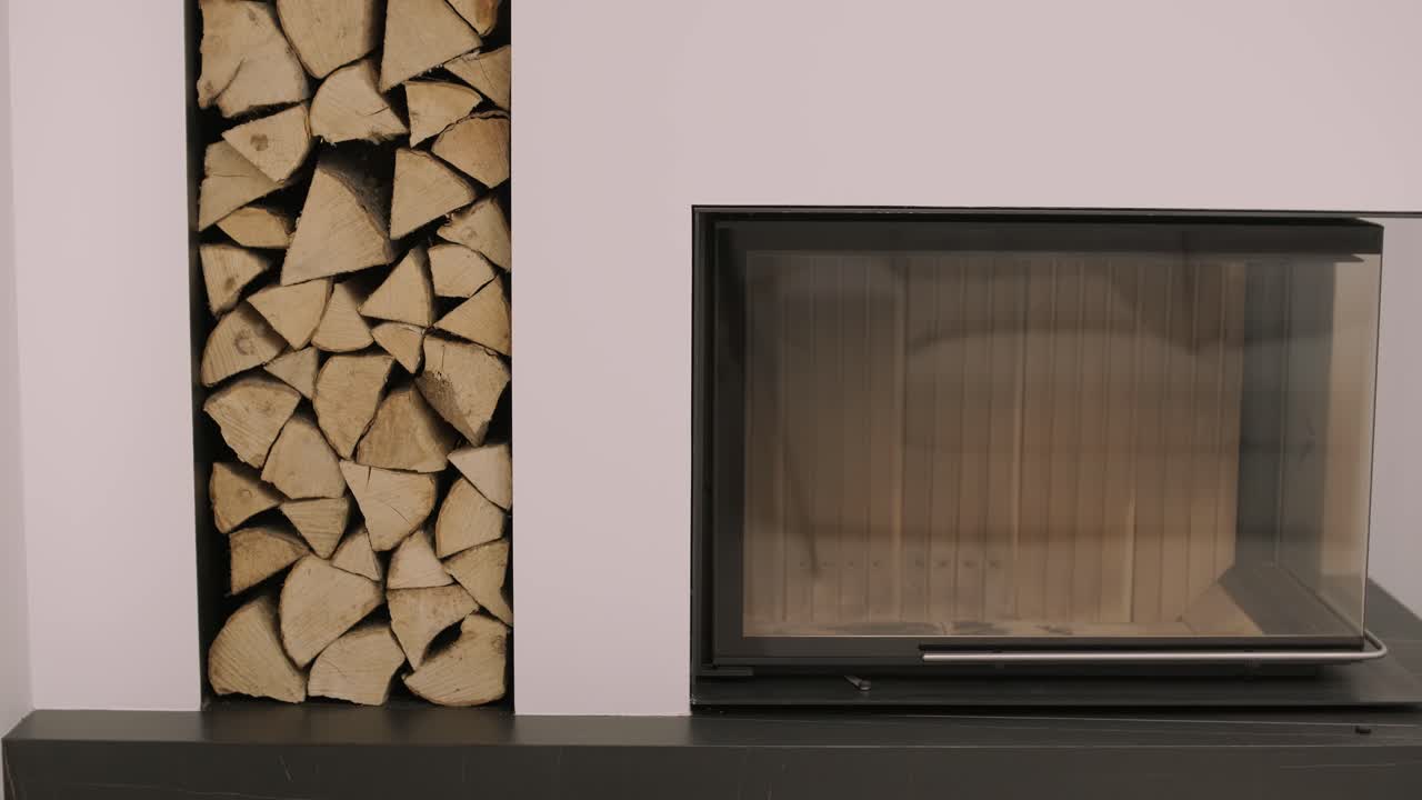 роскошный современный дизайн камина с горящим дровами, дверь с огнестойким стеклянным окном. современный стильный камин и специальная полка для дров