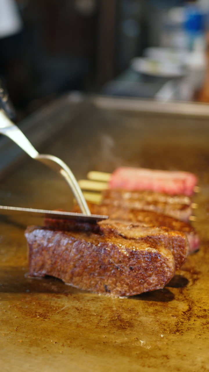 Close up of a vendor frying wagyu beef at the Tsukiji Fish Market in Chuo, Japan. Vertical