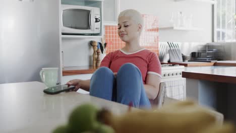 Happy-biracial-woman-holding-smartphone-and-stretching-at-home-in-slow-motion