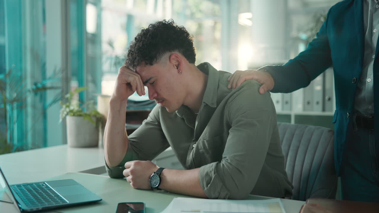 Colleague Comforting Upset Young Man at Office Desk