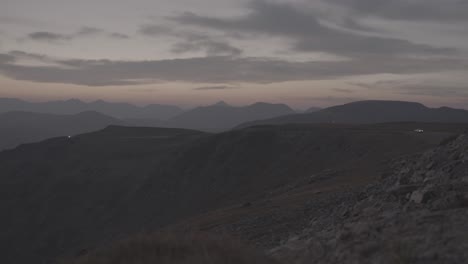 dusk in rocky mountain national park. car lights can be seen in the distance down this mountain road.shot using canon c300 mkiii.