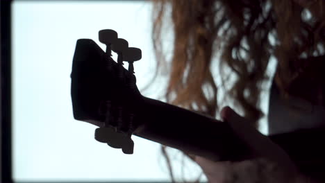 primer plano, estilo dramático hombre de pelo rojo largo tocando la silueta de la guitarra acústica fondo de luz blanca