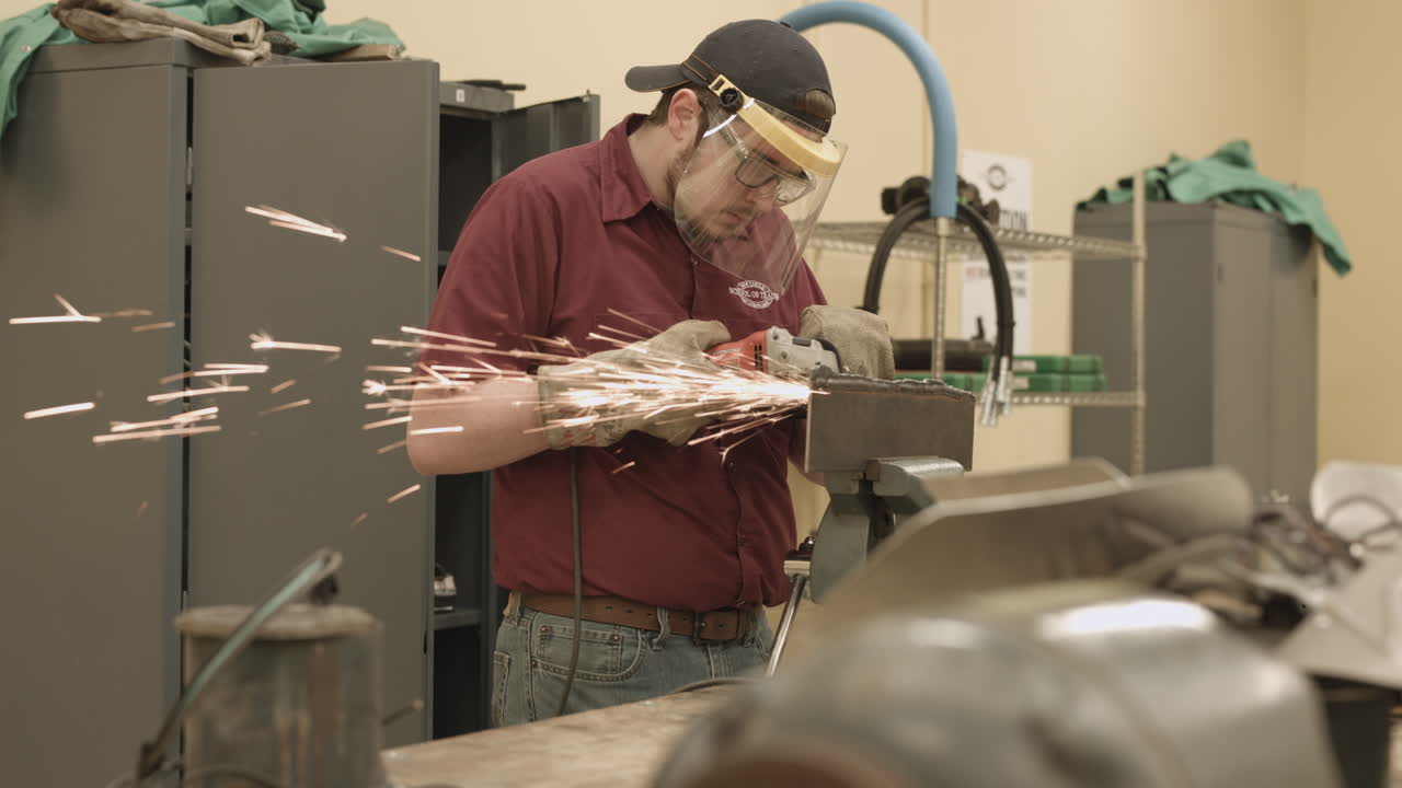 Student apprentice cutting metal with a grinder in a trade school workshop