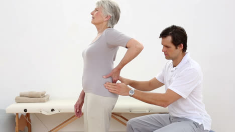 Physiotherapist-touching-senior-patients-lower-back