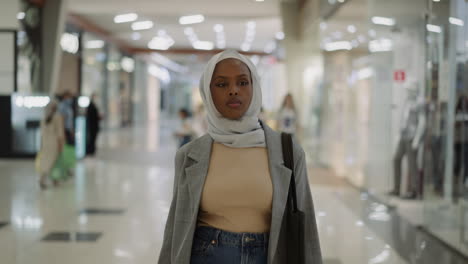 confident african-american woman in hijab walks along mall