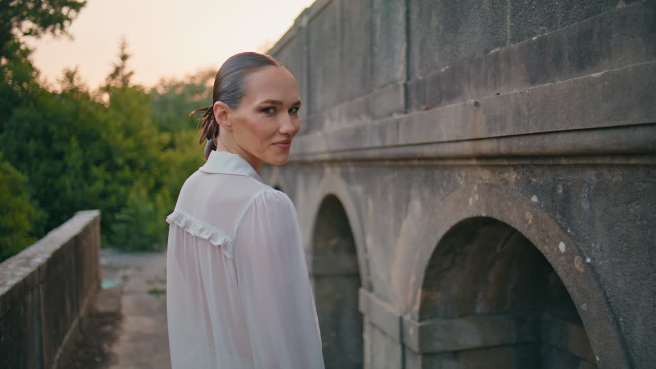 은 건축물을 바라보는 여성 버려진 성은 미소로 카메라로 돌아갑니다.