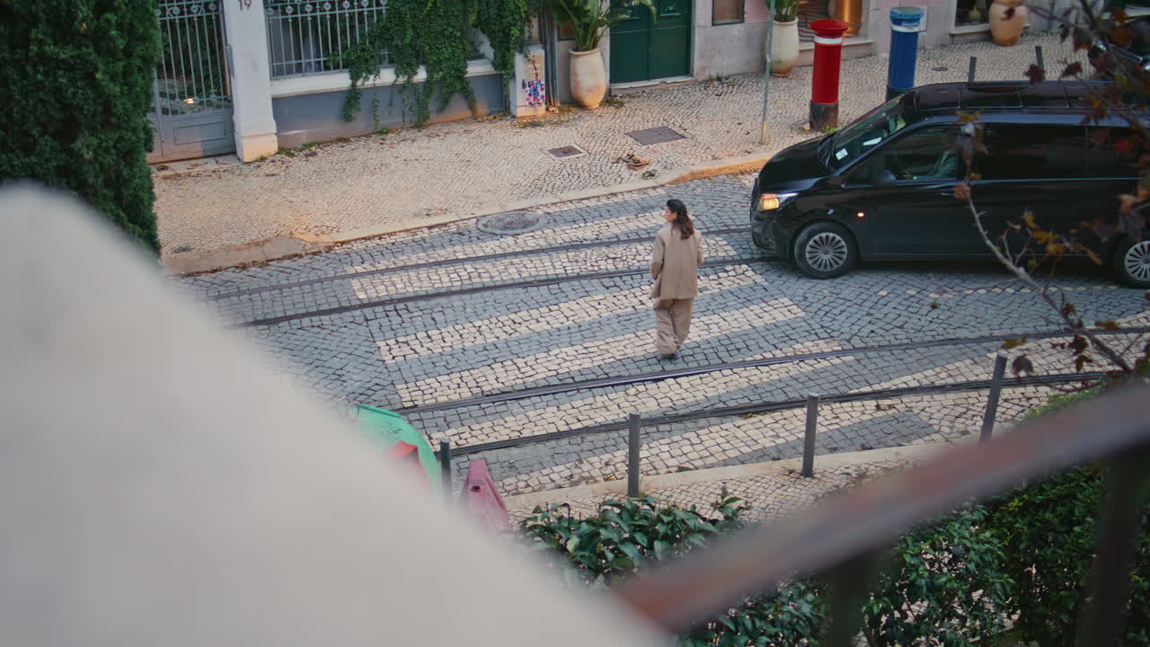 женщина-пешеход, пересекающая дорогу в старом городе. не узнаваемая девушка, идущая по тротуару.