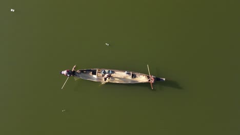 Three-fishermen-netfish-on-an-Asian-river-as-plastic-pollution-floats-by,-highlighting-environmental-impacts-on-traditional-fishing-practices