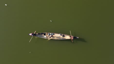 tres pescadores pescan con red en un río asiático mientras flota la contaminación plástica, destacando los impactos ambientales en las prácticas pesqueras tradicionales