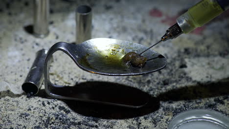 heroin cooking in spoon preparing for drug being sucked by syringe for injection