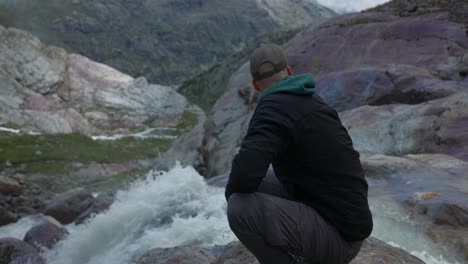 man with action cam looks over stunning waterfall in italian mountains