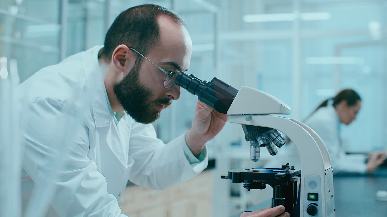 Scientist Observing Specimen through Microscope in Research Laboratory