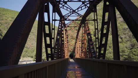 old iron railway bridge, tilt reveal over empty hiking trail, takedao japan