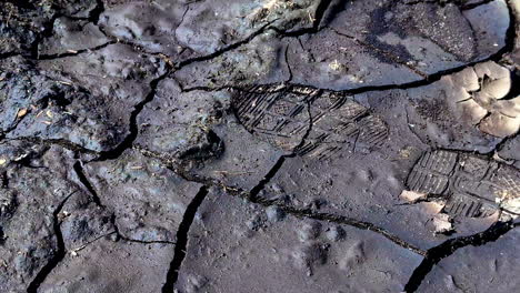 huellas en tierra seca y agrietada que muestran evidencia de presencia humana en un paisaje estéril