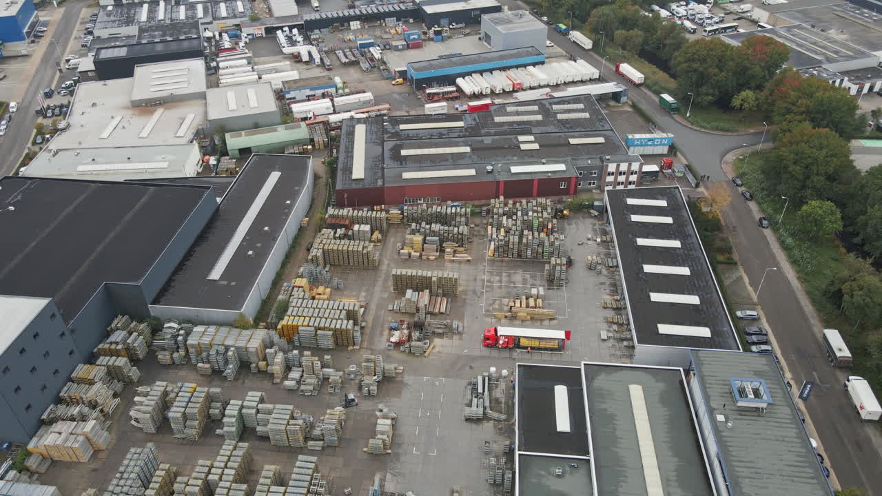 Beautiful aerial of a busy industrial storage yard with forklift trucks driving between high stacks of construction materials while a truck is being loaded with cargo