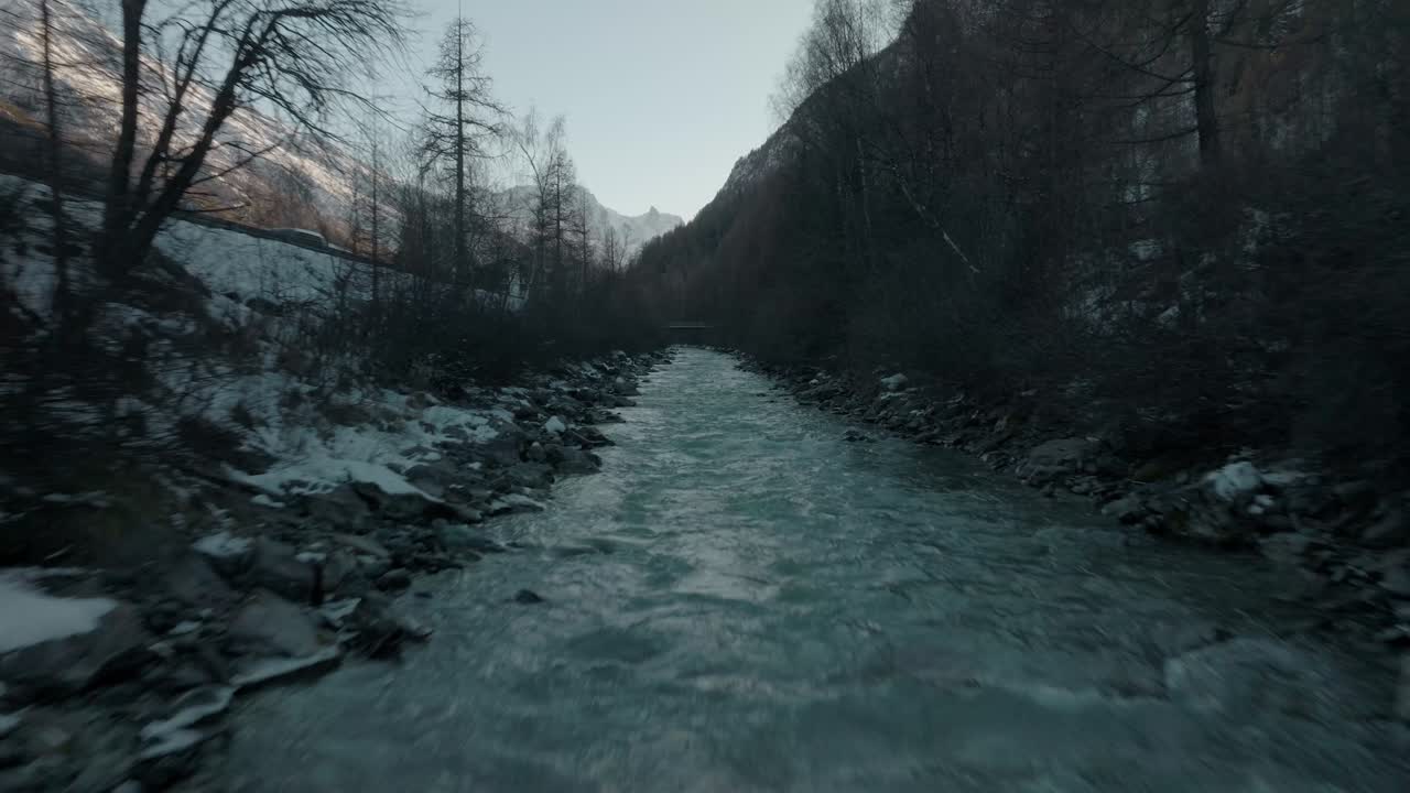 carro rápido sobre la corriente de agua del río suizo frío con nieve en las orillas del río en los alpes suizos con un panorama épico de montaña