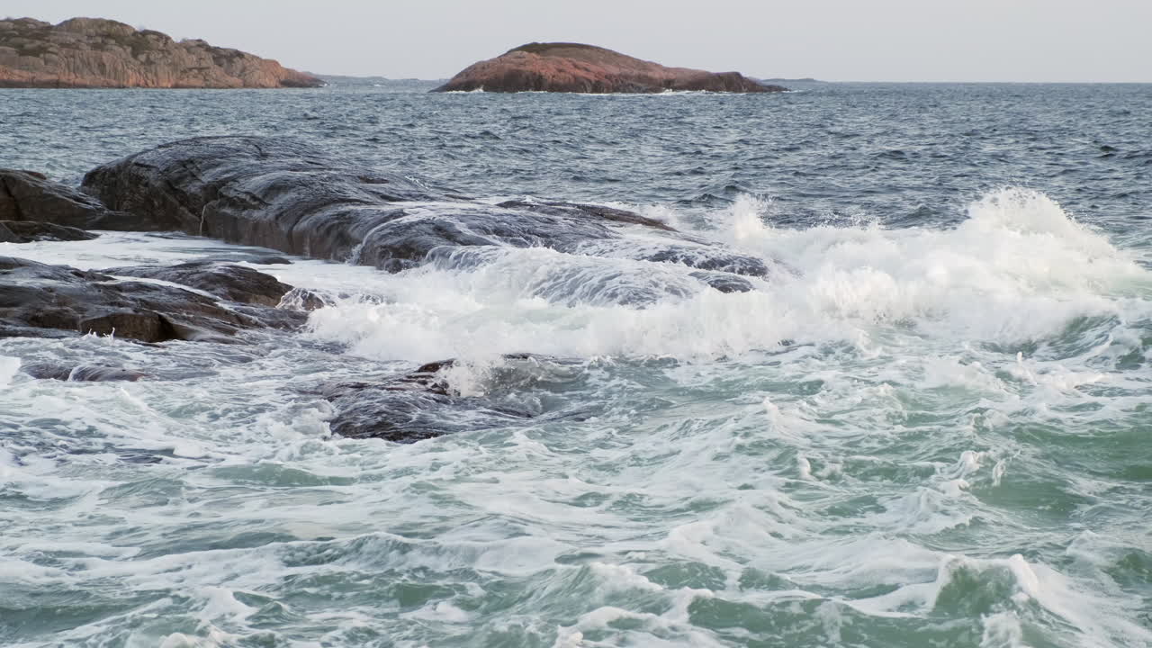 Waves hitting rocks. Evening shot. Dark ocean, white waves. Slow motion.