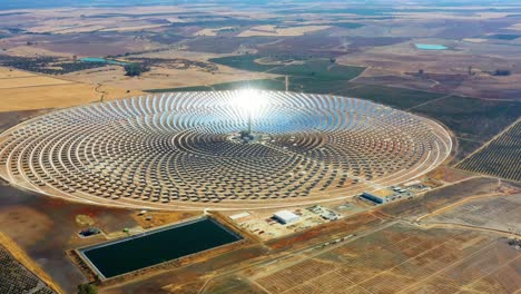 vista aérea de una gran planta de energía circular de paneles solares en españa. hay el reflejo del sol en los paneles que producen energía renovable - concepto de medio ambiente