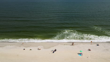 aerial drone shot pan left facing the ocean looking at the shoreline and the different people on the beach