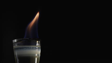 video de alcohol encendido en vidrio con llama de fuego naranja y copia de espacio en fondo negro