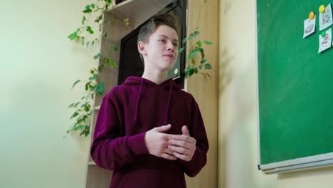 schoolboy answering the teacher. clever teen student standing near the blackboard in the classroom and talking. education at school.