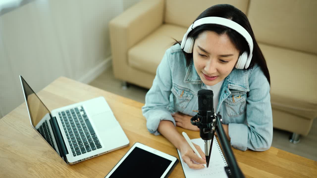 Content creator woman host streaming his a podcast on laptop with headphones and microphone interview cheering guest conversation at broadcast studio. Blogger motivation recording voice over radio.