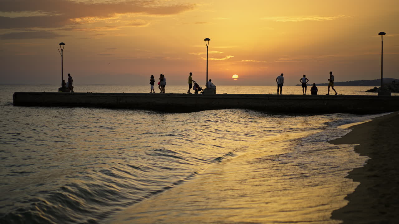 People enjoying a sunset at the beach on a pier