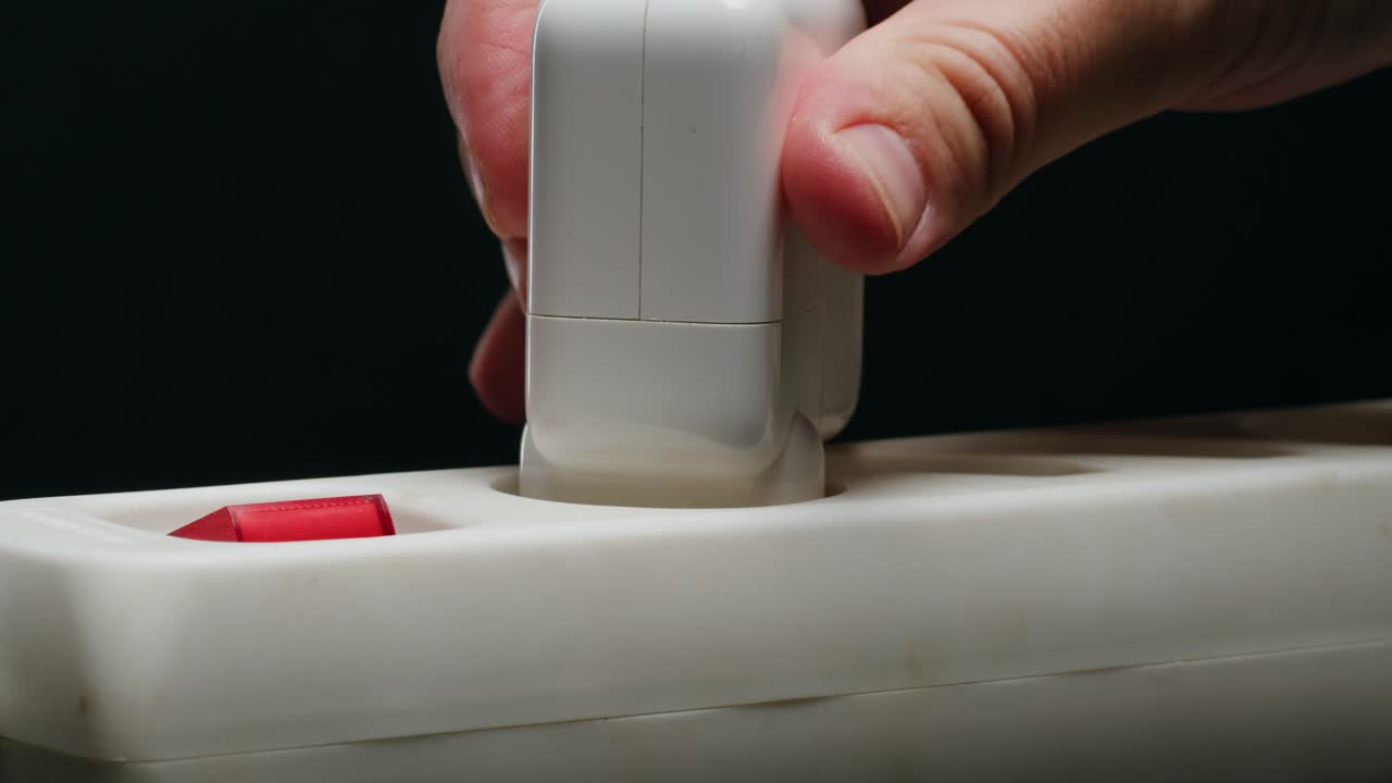 Hand plugging a device into a power strip