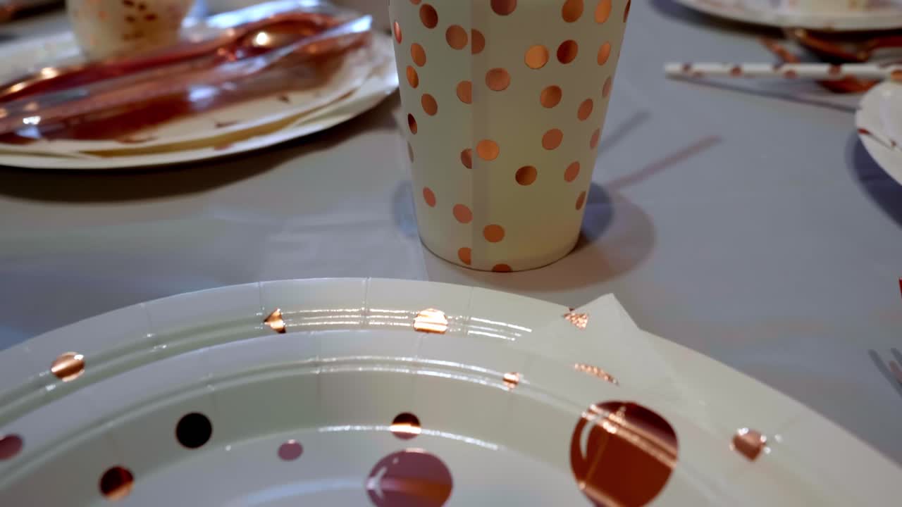 A white paper plate with "Happy Birthday" in gold cursive sits on a white tablecloth, surrounded by matching gold polka dot plates and a gold fork
