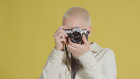 modelo caucásica femenina posando con slr vintage contra fondo amarillo 04