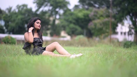 a beautiful and hot asian girl wearing short black dress is relaxing and combing her hair with fingers in sensous way