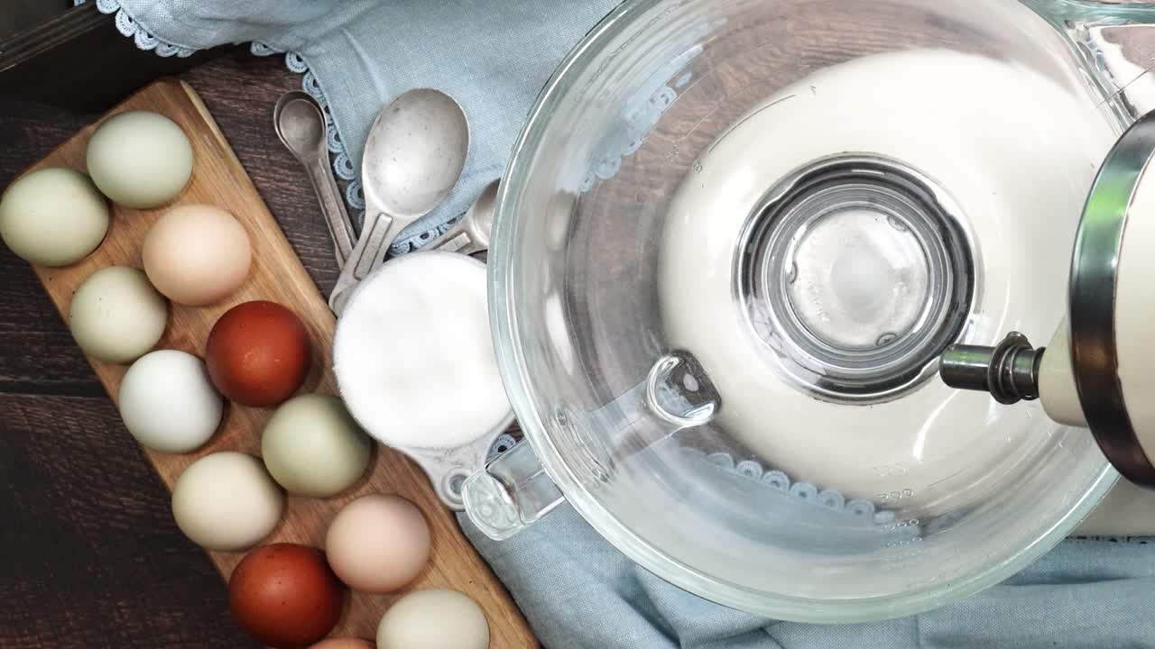 Baking a dessert and using an electric mixer to combine ingredients. Mixing baking ingredients to make brownies for a dessert. Dozen eggs beside an electric mixer while combining baking ingredients