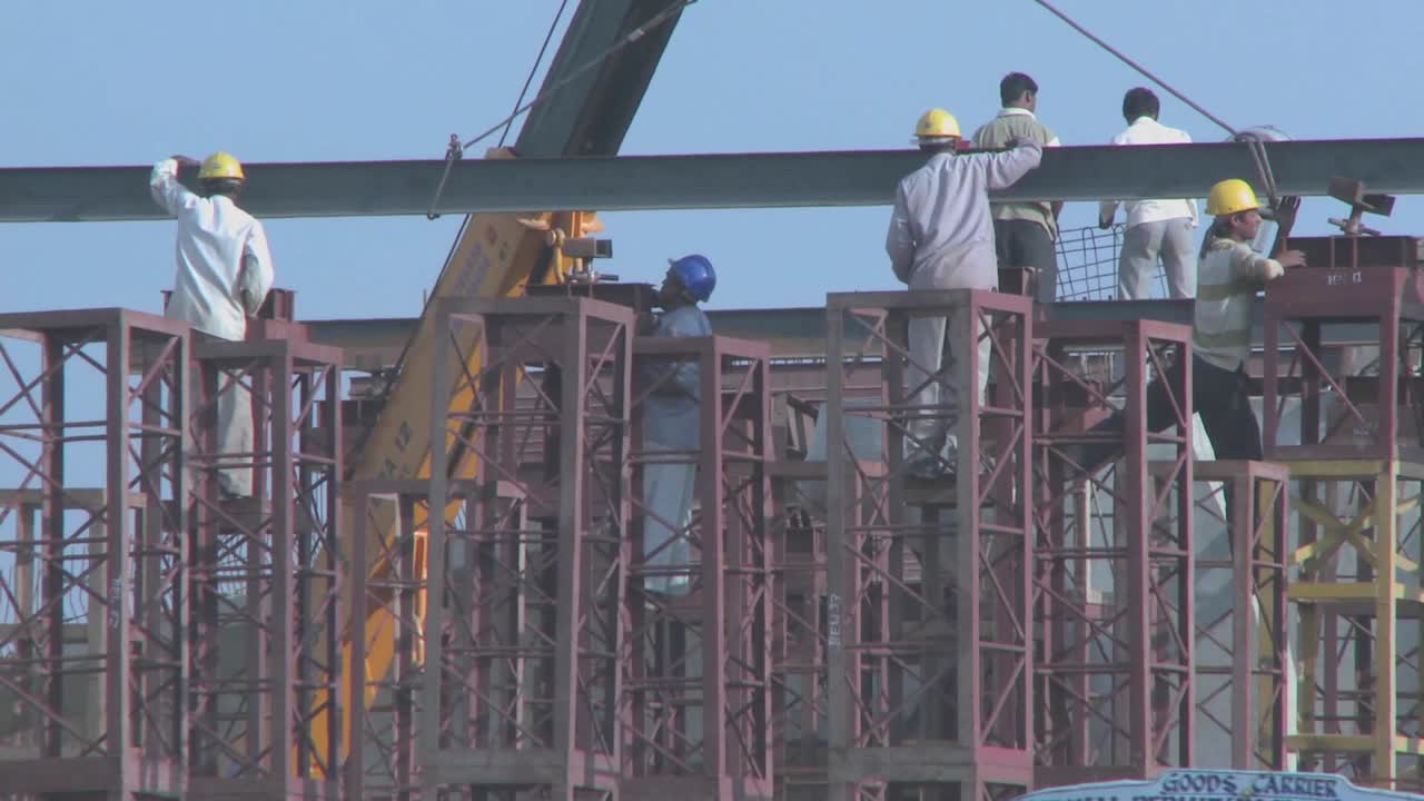 Widening view of construction workers and the traffic and vehicles traveling on the streets