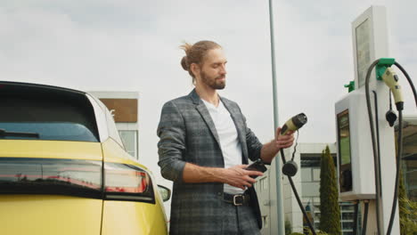 hombre cargando un coche eléctrico en la estación
