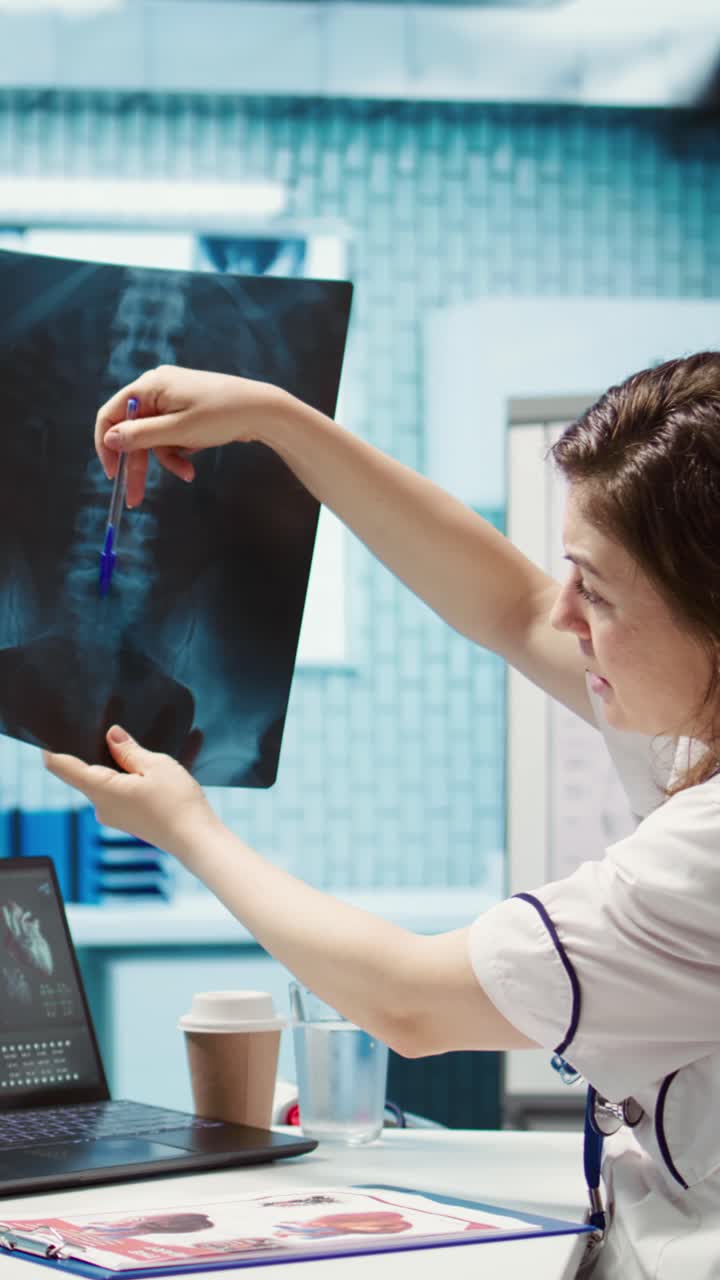 Dottoressa che esamina una lastra radiografica e usa un laptop in clinica