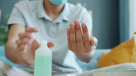 person washing hands with hand sanitizer wearing a mask