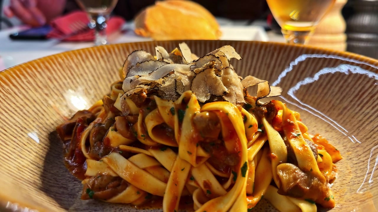 Primo piano di tagliatelle condite con scaglie di tartufo e una salsa ricca su un tavolo di ristorante a Bellagio, Italia