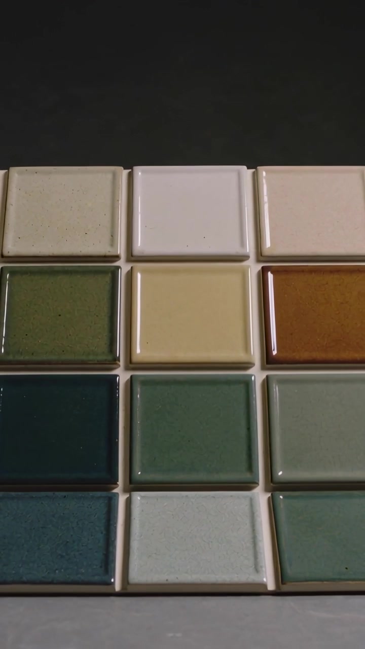 Vídeo vertical: Câmera inclinando, mostrando folha de amostras de azulejos na bancada, revelando rejunte e brilho.