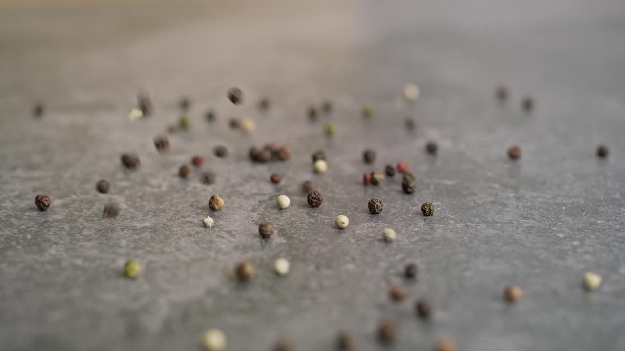 Detail-Video von buntem Pfeffer, der auf eine Küchenarbeitsplatte fällt.
