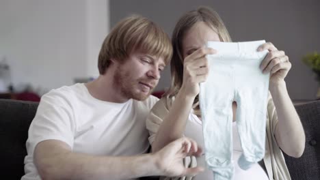 vista frontal de una feliz pareja joven mirando ropa para niño