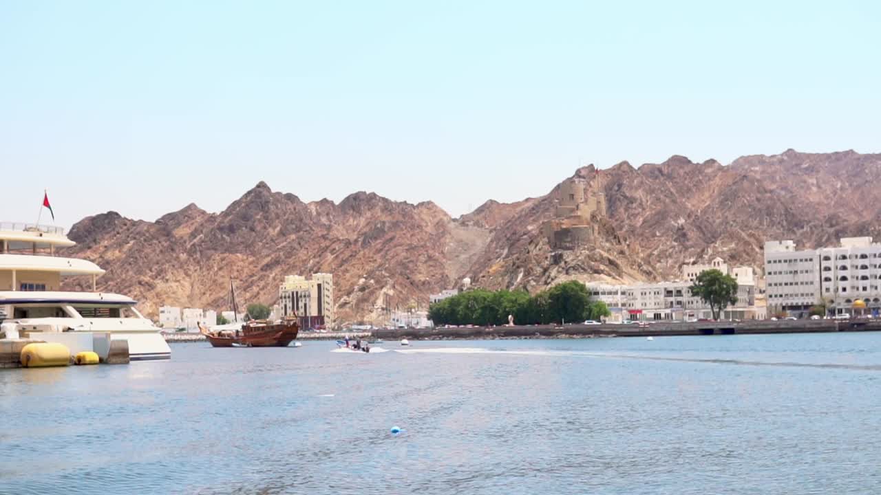 un puerto local cerca de muscat, omán, oriente medio con yates, barcos, montañas y edificios en el fondo