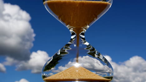 hourglass against a blue sky with clouds