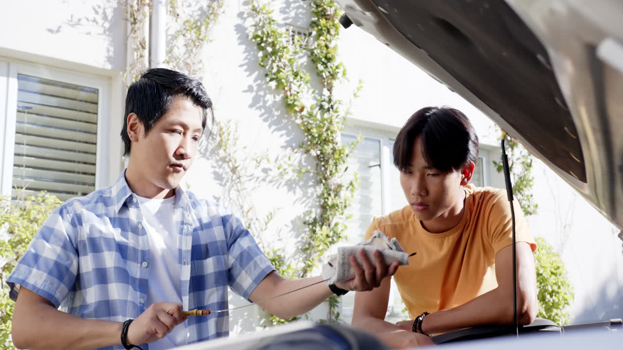 Checking car engine, asian father and son discussing maintenance in outdoor setting