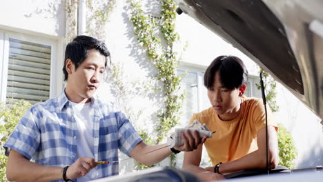 checking car engine, asian father and son discussing maintenance in outdoor setting