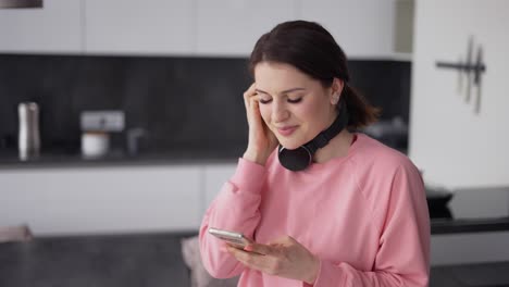 Mujer-Joven-Y-Guapa-Con-Auriculares-Bailando-En-La-Cocina-Y-Escuchando-Música