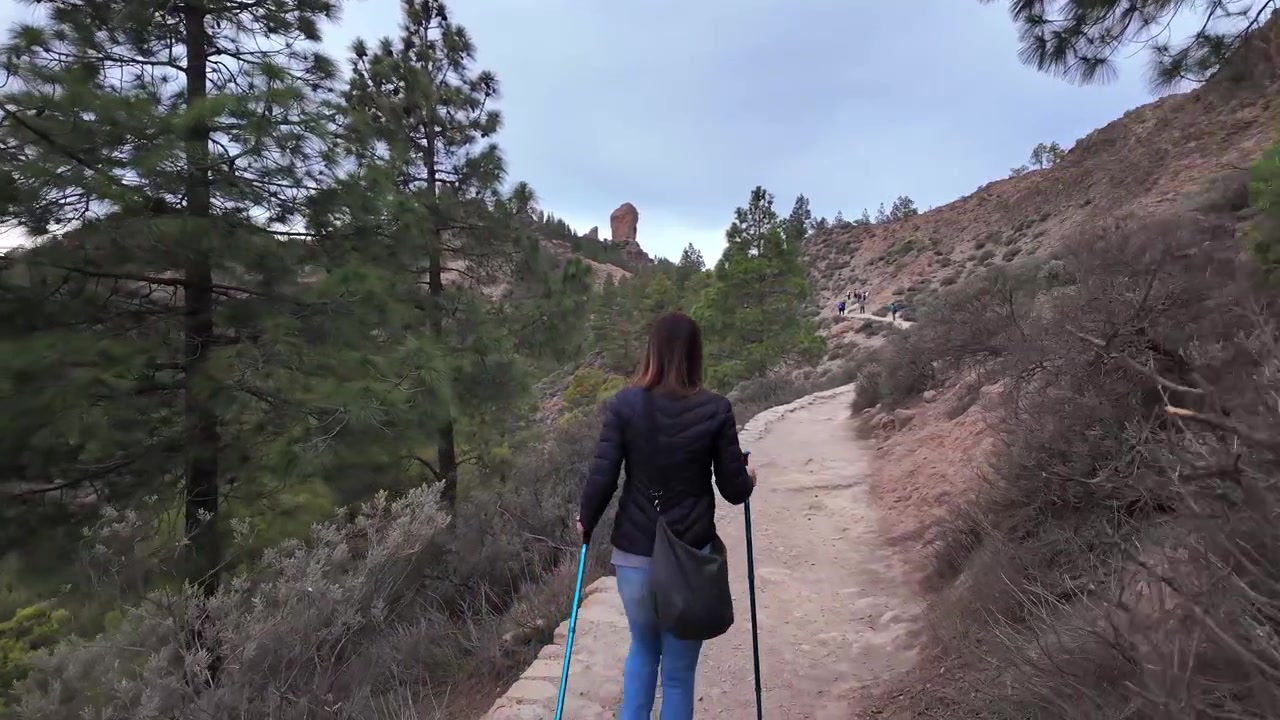 Donna escursionista che cammina su un sentiero panoramico con bastoncini da trekking. Stile di vita sano e attività all'aperto nelle montagne di Gran Canaria