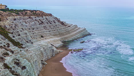 Disparo-En-ángulo-Alto-Sobre-La-Scala-Dei-Turchi,-Un-Acantilado-Rocoso-En-La-Costa-Sur-De-Sicilia,-Italia,-Con-Olas-Rompiendo-En-Timelapse-Durante-El-Día