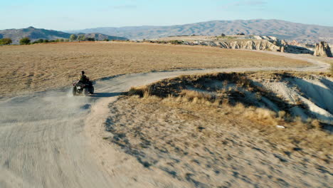 Young-girl-riding-a-quad-bike-through-the-arid-landscapes-of-Cappadocia,-Turkey