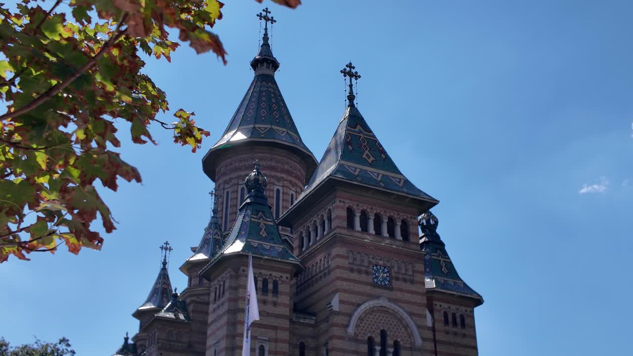 Scenic view of Timisoara’s Metropolitan Cathedral with natural foliage in the foreground, adding depth and charm to the landmark