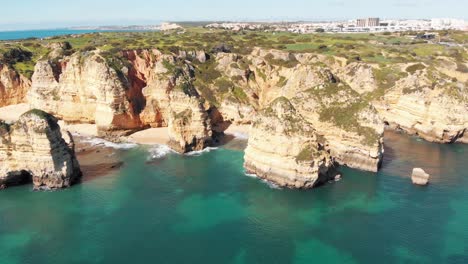 Calas-De-Arena-íntimas-Rodeadas-De-Imponentes-Acantilados-Erosionados-En-Lagos,-Algarve,-Portugal---Toma-Aérea-Amplia-De-Retorno